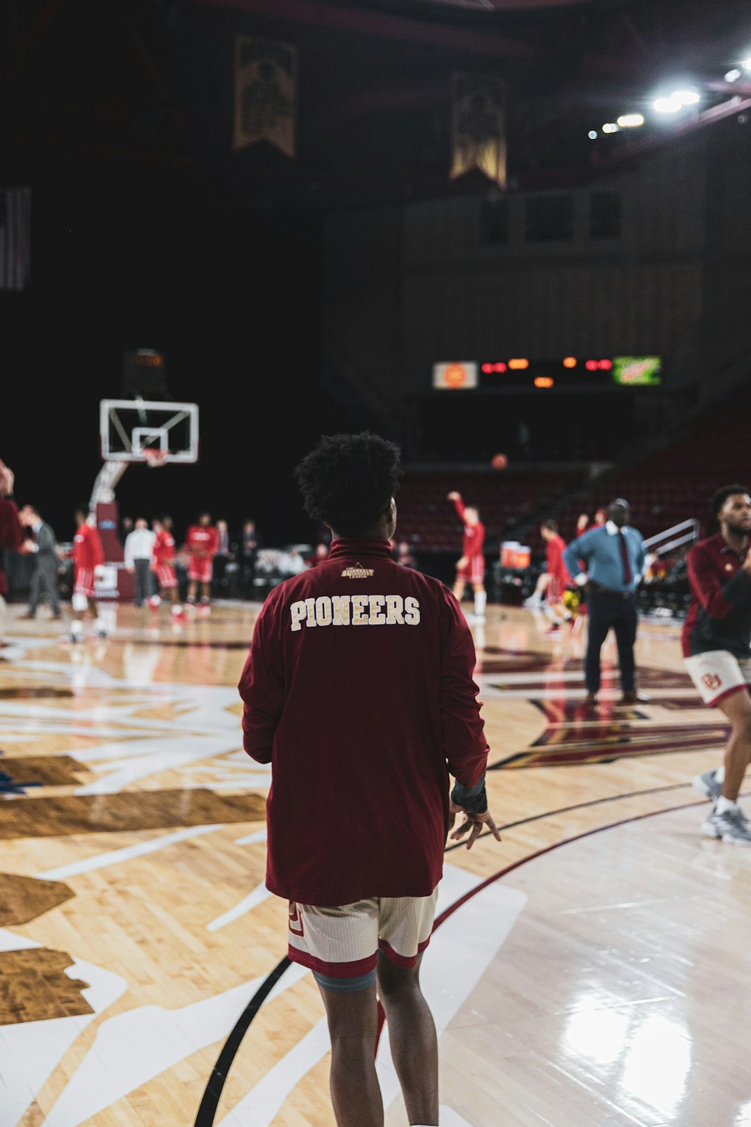 man in red and black jersey shirt standing on basketball court