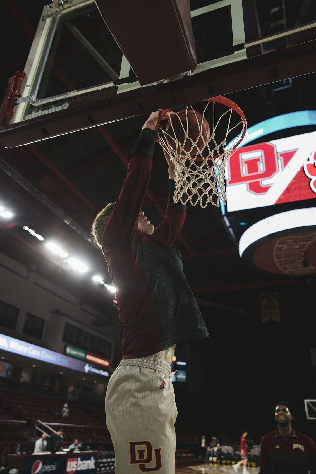 man in gray shirt and brown pants holding blue and red basketball hoop