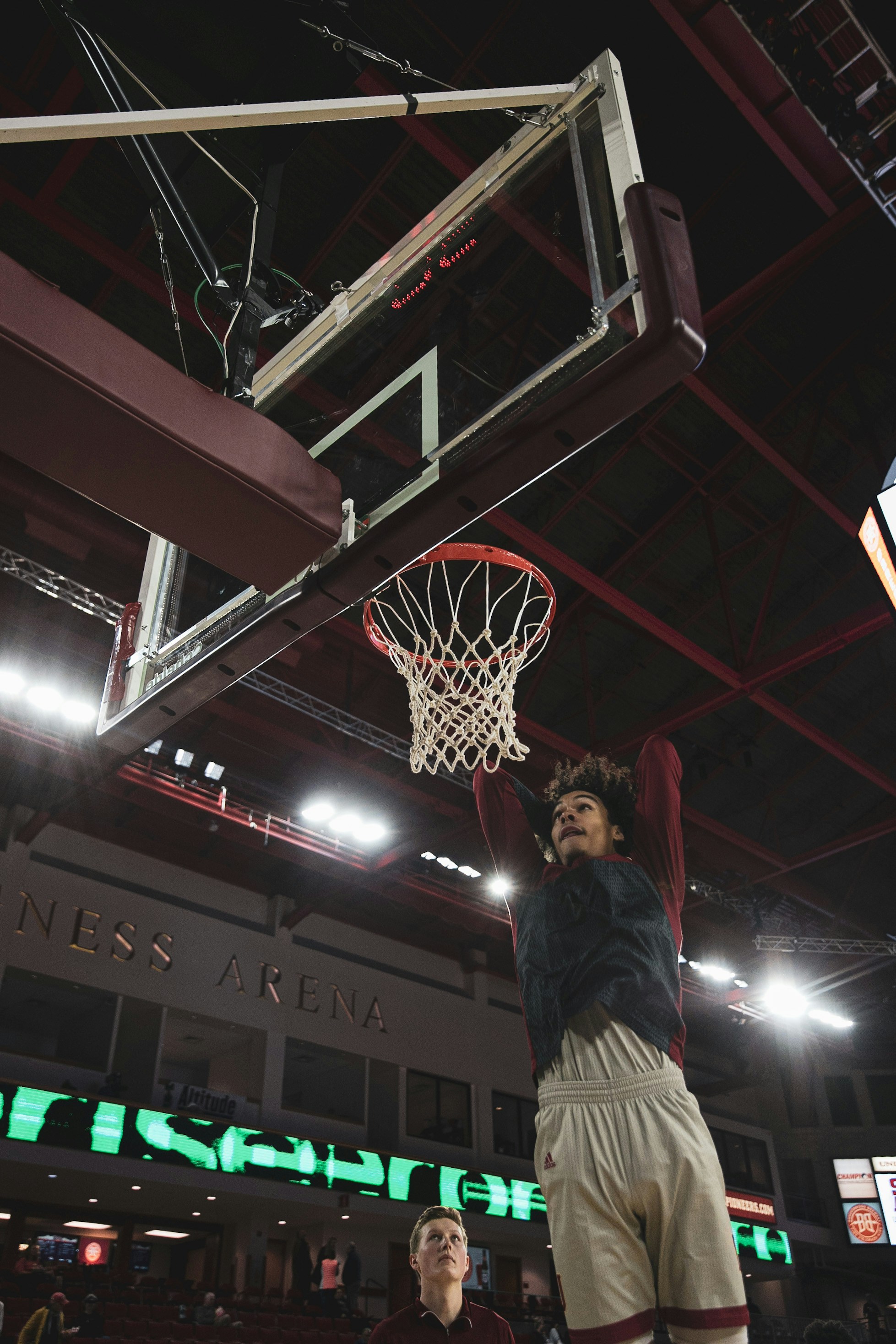 Basketball player dunking during a high-energy NBA game in a packed indoor arena with dramatic court lighting