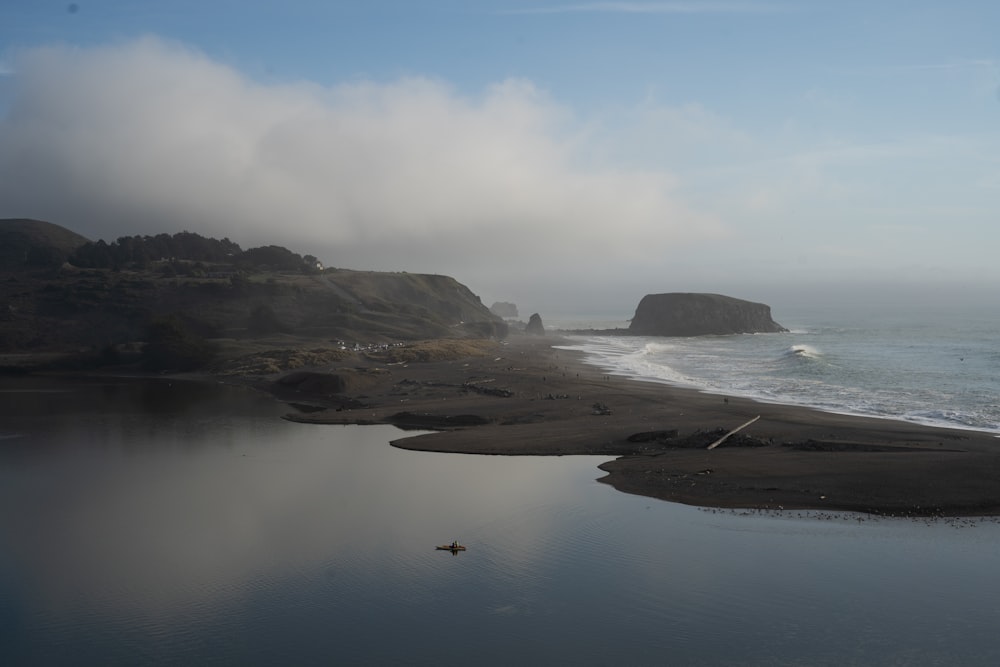 brown rock formation on body of water during daytime