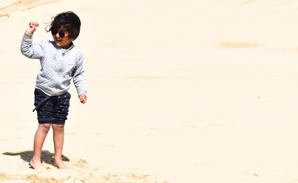 boy in gray long sleeve shirt walking on brown sand during daytime