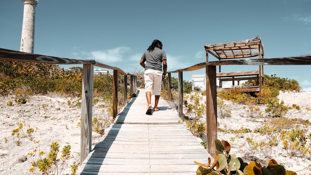 man in gray t-shirt and gray shorts standing on brown wooden dock during daytime