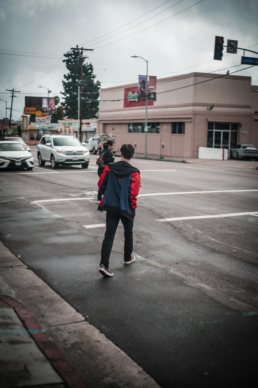 woman in red jacket standing on road during daytime