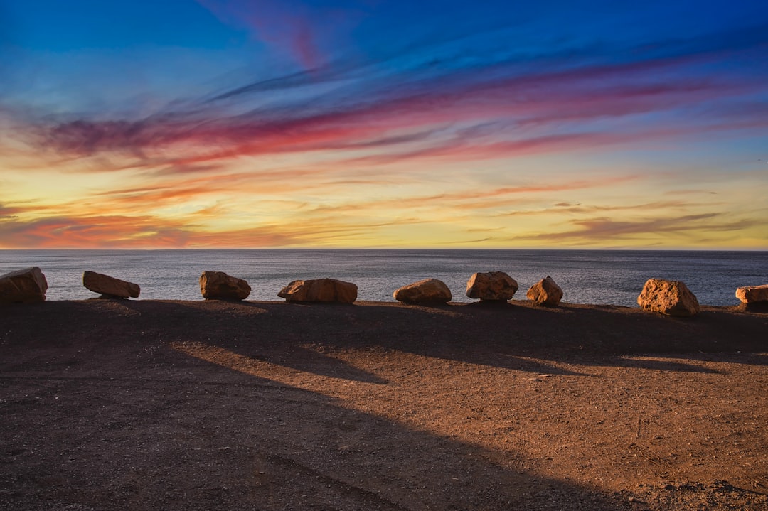 brown rocks on brown sand near body of water during sunset