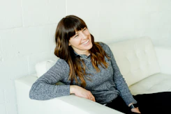 woman in gray sweater sitting on white chair