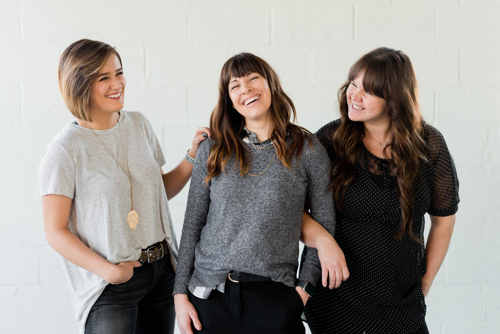 Three women laughing together in a bright studio