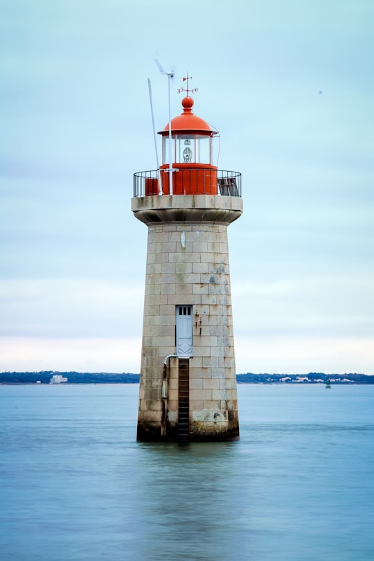 white and red lighthouse on body of water during daytime in Saint-Nazaire France