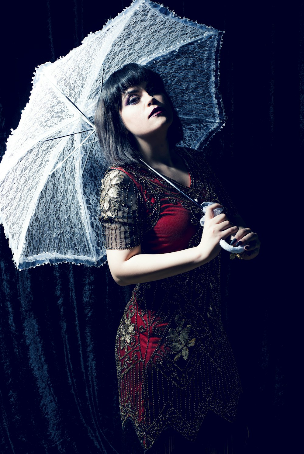 Femme en robe rouge et noire tenant un parapluie