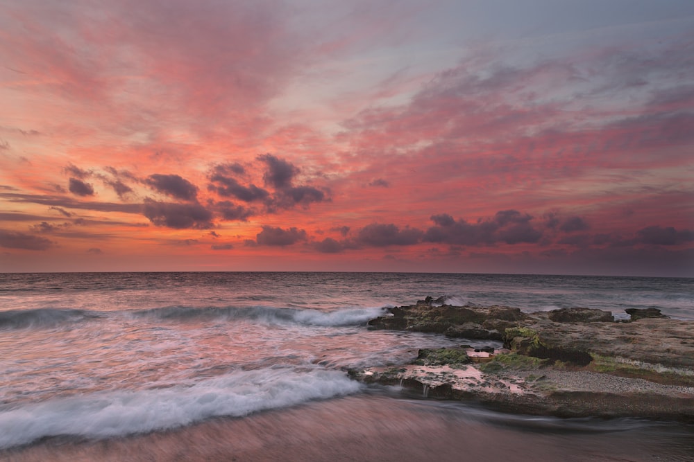 ocean waves crashing on shore during sunset