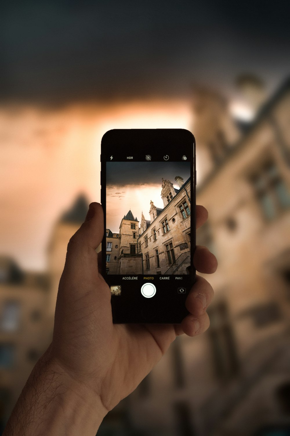 pessoa segurando iphone 4 preto tirando foto de edifícios da cidade durante o dia