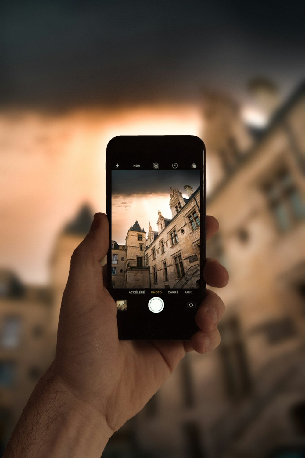 person holding black iphone 4 taking photo of city buildings during daytime