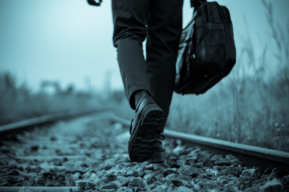 person in black pants and black leather boots walking on the street