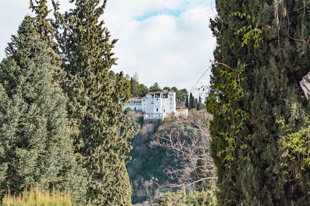 Une grande maison blanche assise au sommet d’une colline verdoyante