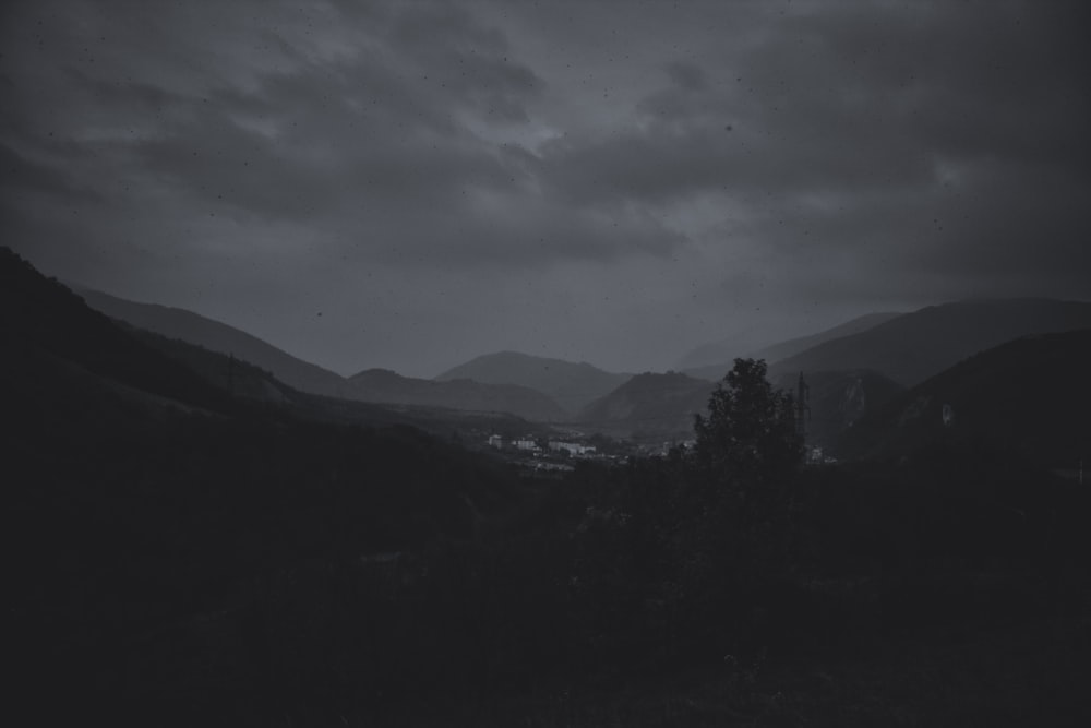 green trees and mountains under cloudy sky during daytime