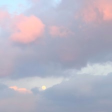 A gentle pastel pink moon glowing softly against a twilight sky.