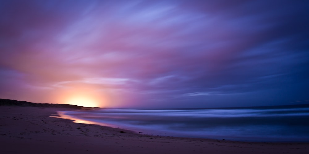 body of water under cloudy sky during sunset