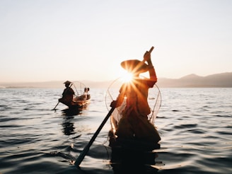 silhouette of 2 men riding on boat during sunset