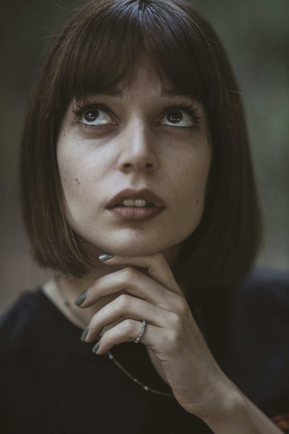 woman in black shirt holding her chin