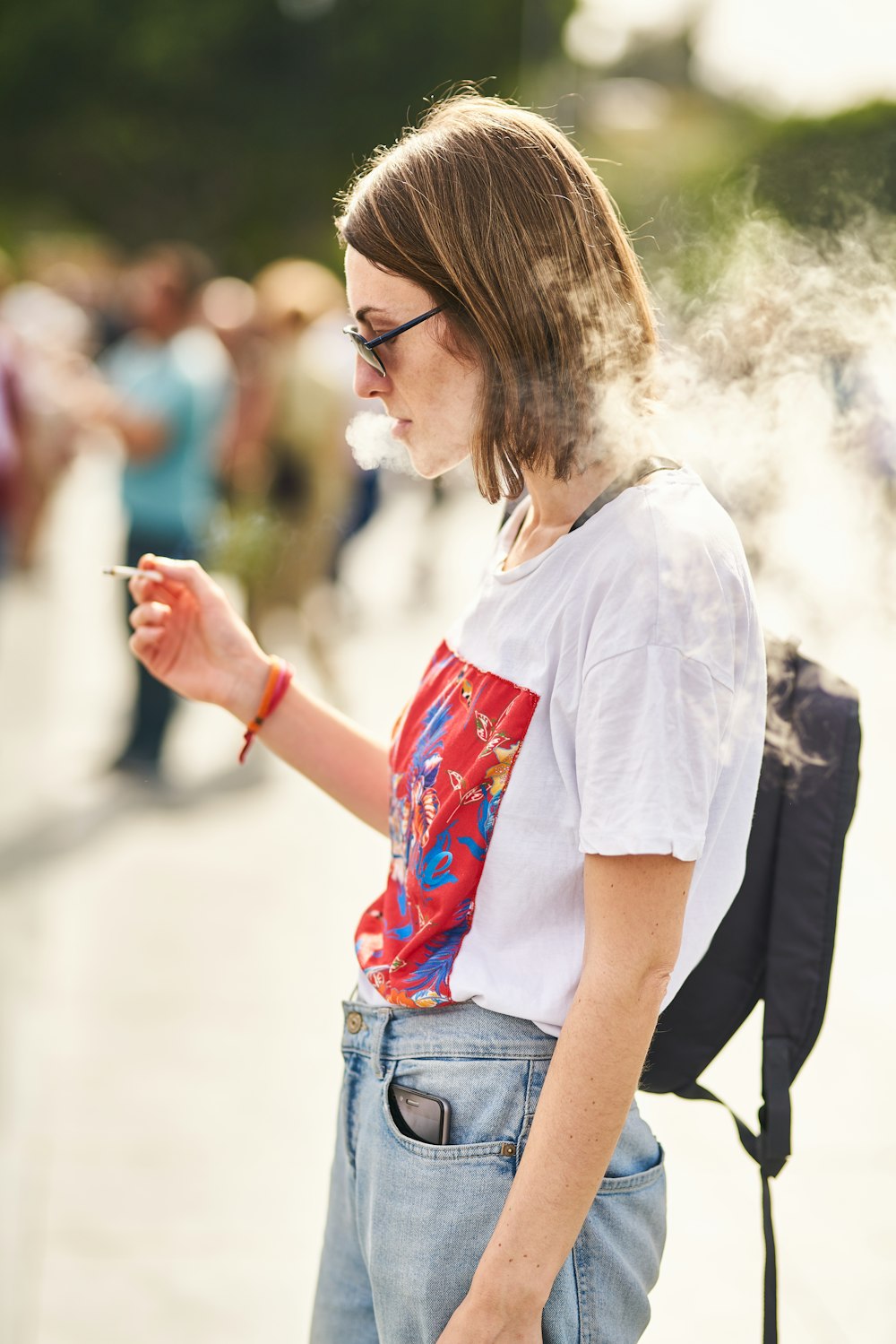 woman in white t-shirt and blue denim jeans holding smartphone