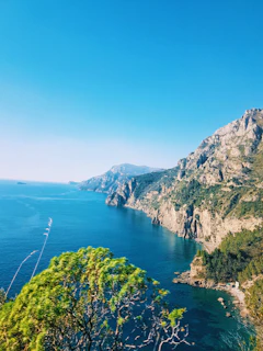 A dramatic coastal cliff view along the rugged shores of Cornwall under a bright blue sky.