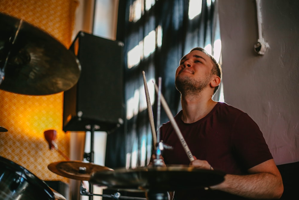 man in red crew neck shirt playing drum