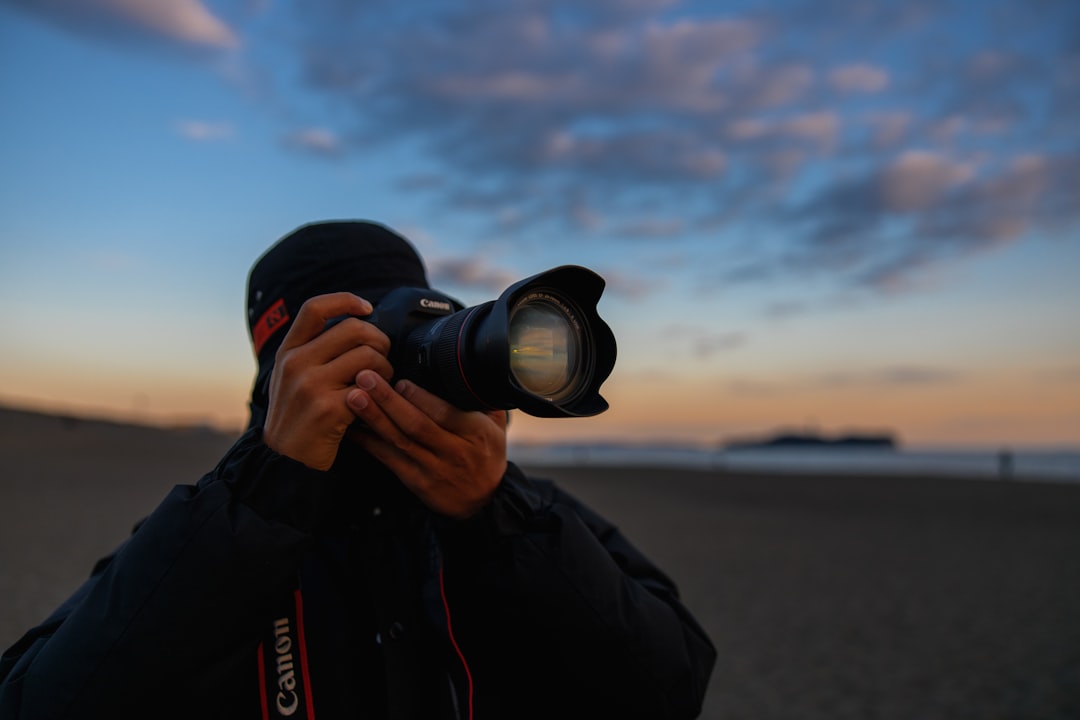 man in black jacket holding black dslr camera