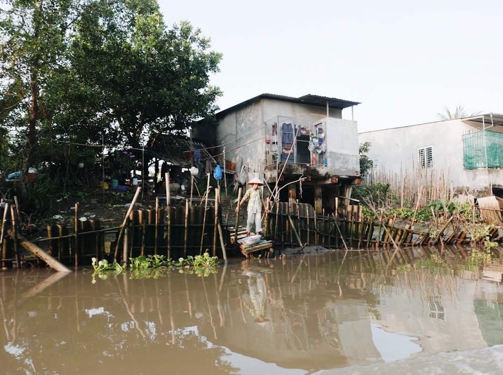 white and brown wooden house beside green trees and body of water during daytime