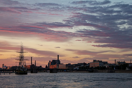 A panoramic view of a ship anchored at a bustling port during sunset.