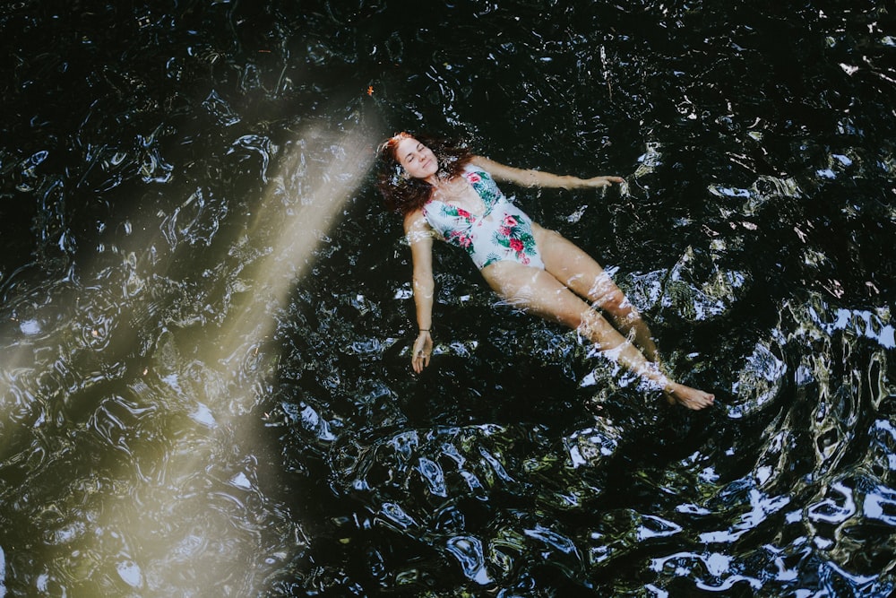 donna in bikini floreale blu e bianco sdraiata sull'acqua