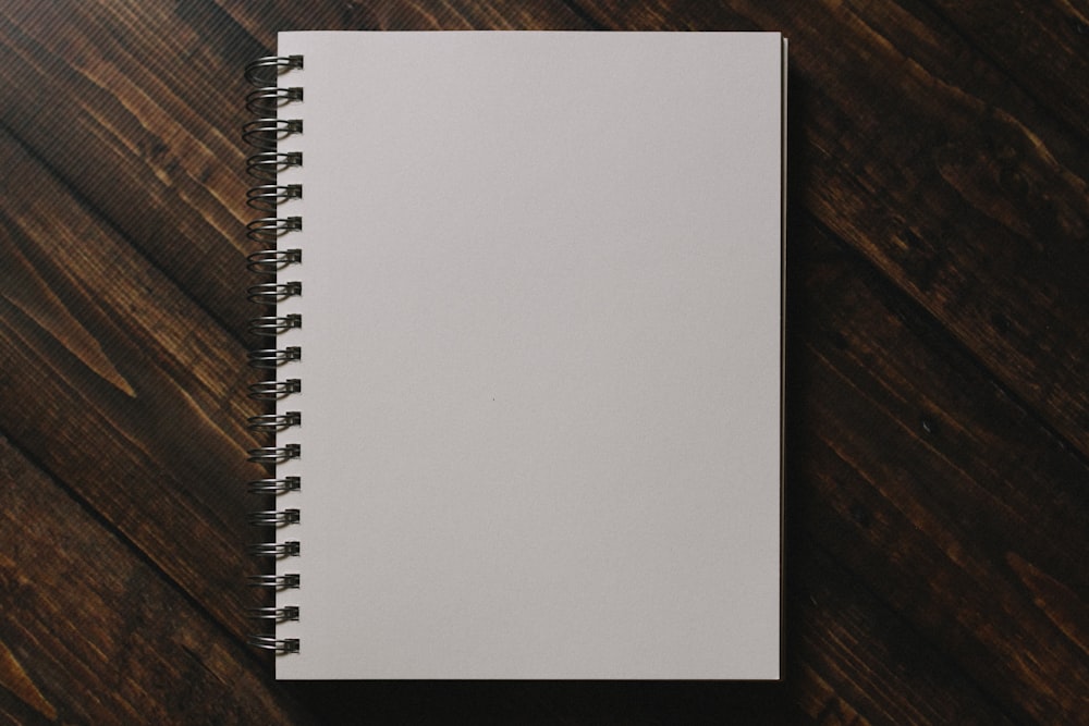 Cuaderno de espiral blanco sobre mesa de madera marrón