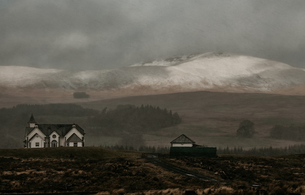 white and black house near green grass field under white clouds during daytime