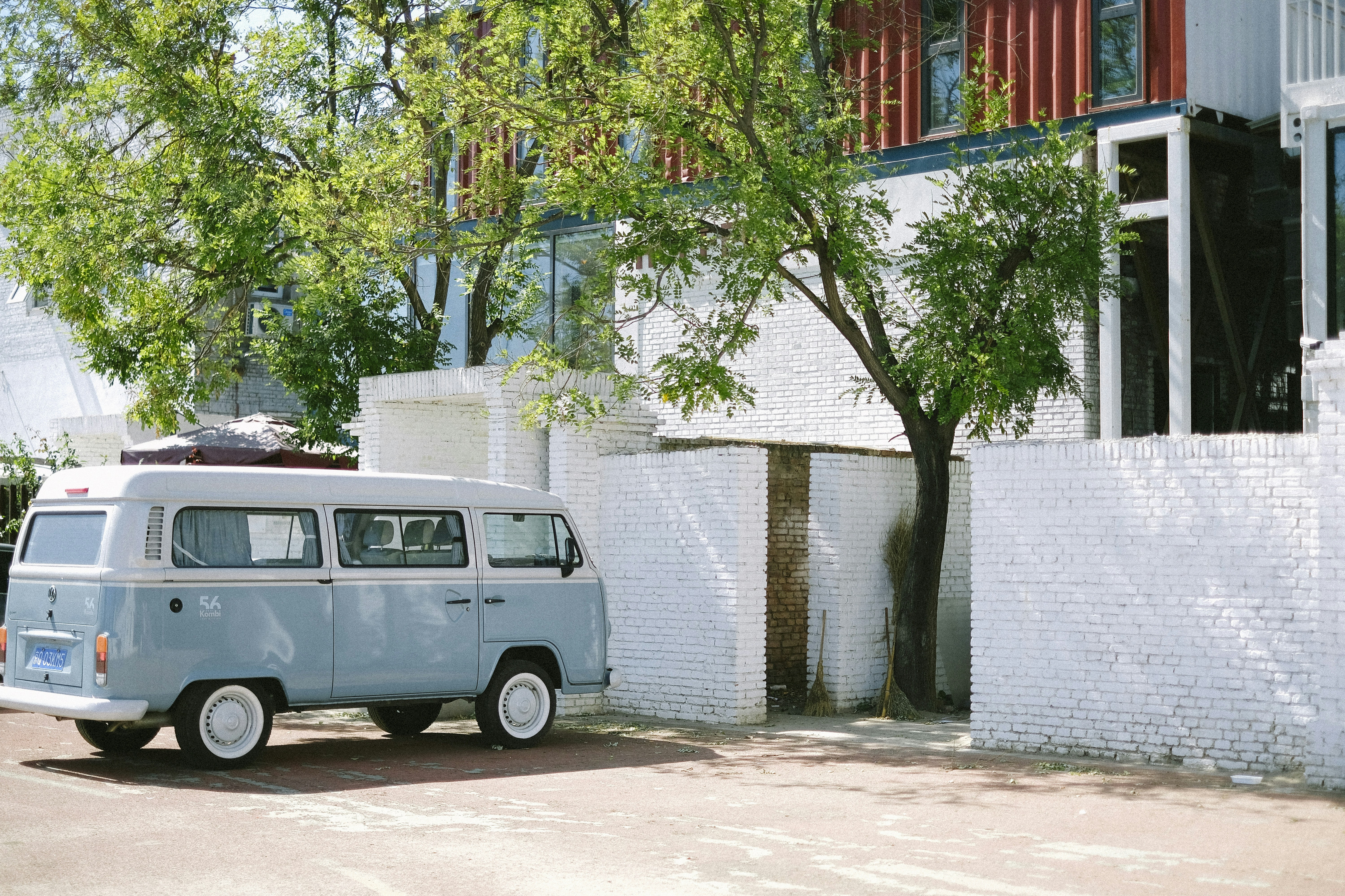 blue and white volkswagen t-2 parked beside brown concrete building during daytime