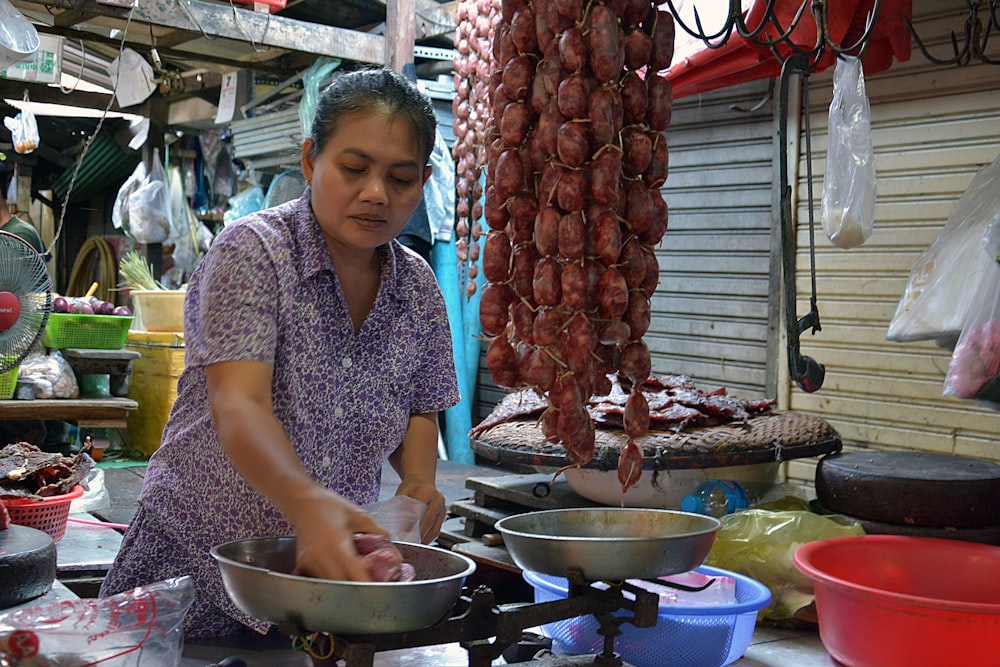 woman in blue and white polka dot shirt standing near raw meat