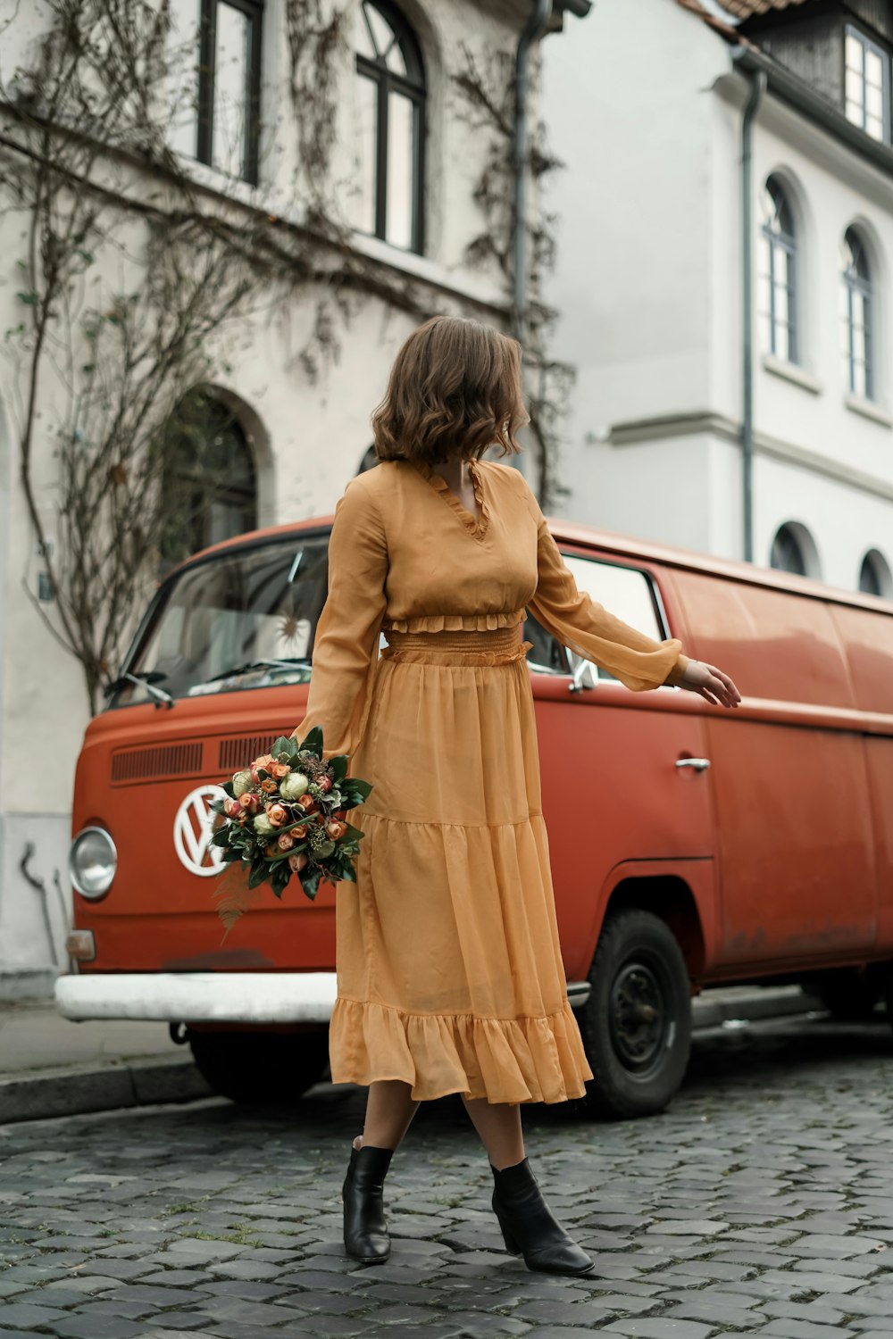 woman in yellow long sleeve dress leaning on red car during daytime