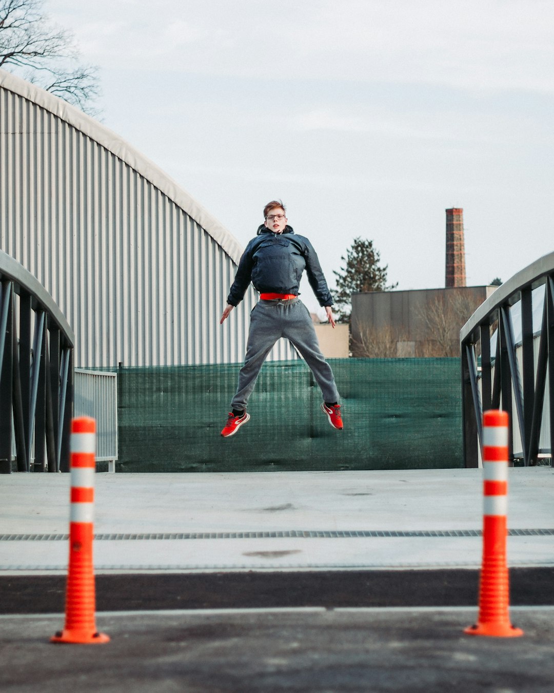 man in black jacket and black pants jumping on gray concrete road during daytime