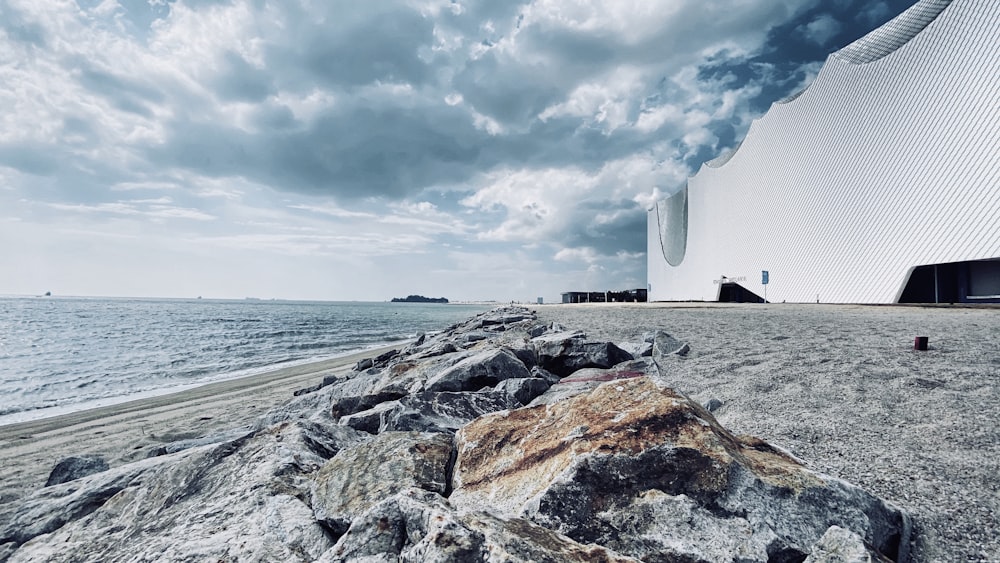white concrete building near sea under white clouds during daytime