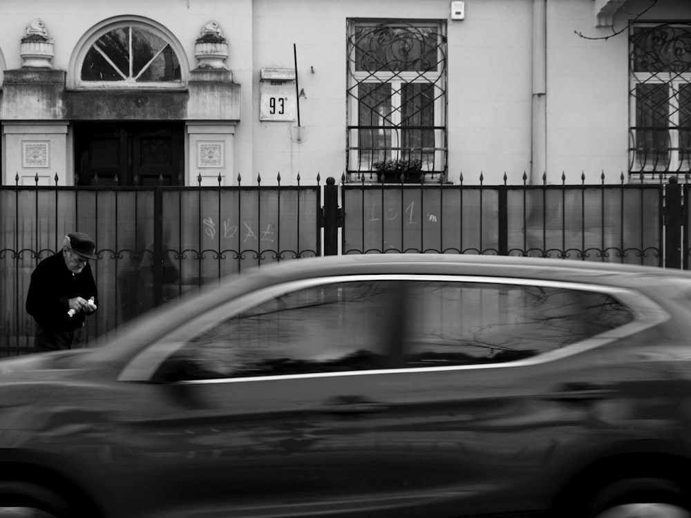 grayscale photo of car in front of building