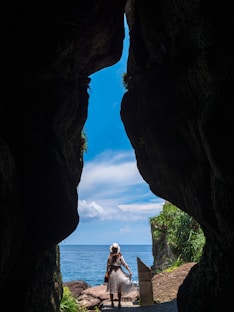 woman in white shirt sitting on rock formation during daytime