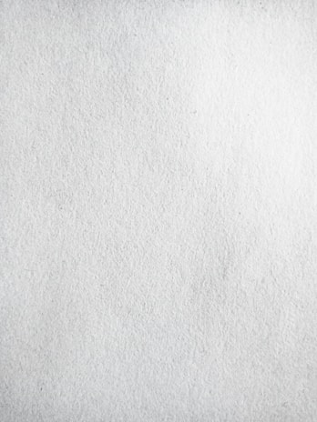 A texture of plain white paper with fine grain, slightly uneven surface.