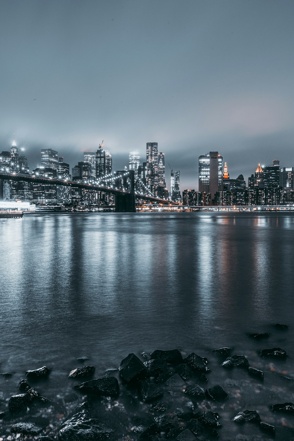 city skyline across body of water during night time