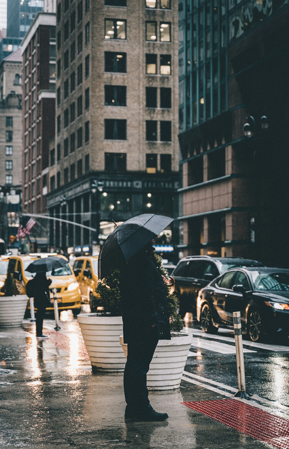 person in black coat holding umbrella walking on pedestrian lane during daytime