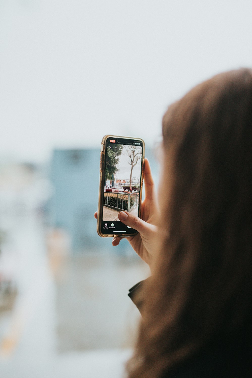 woman holding silver iphone 6 taking photo of white building during daytime