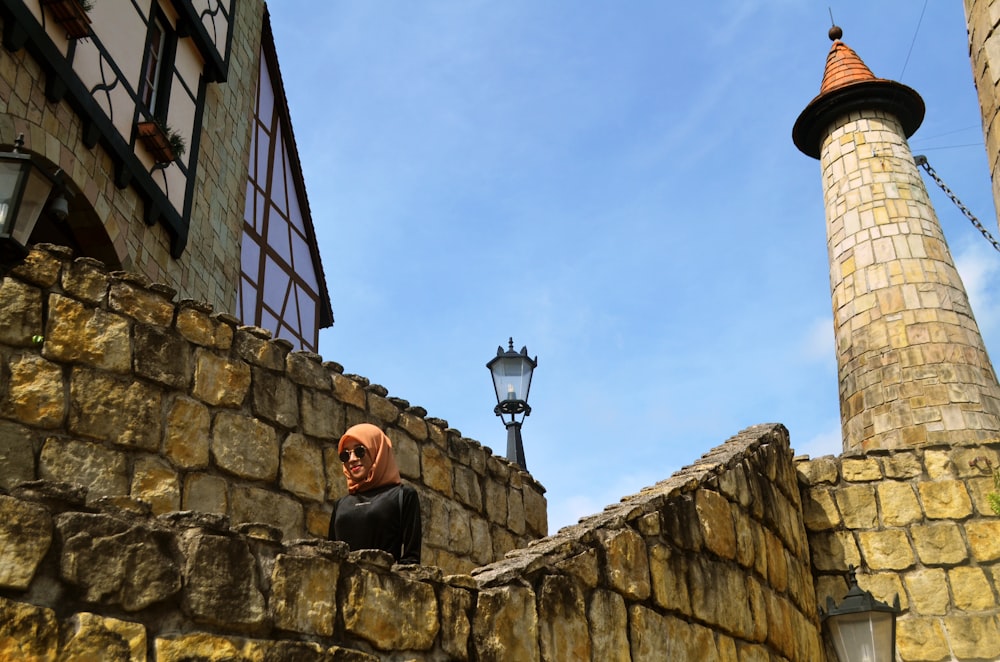 man in black jacket sitting on concrete wall during daytime