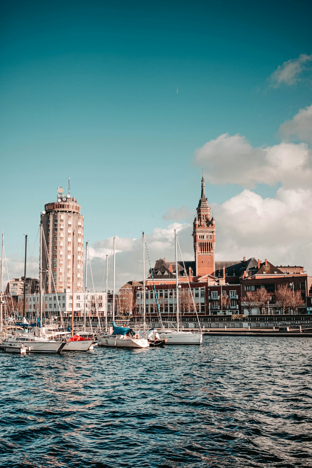 white and blue boat on body of water near city buildings during daytime