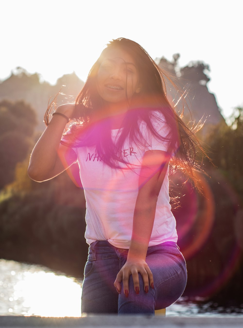 woman in pink t-shirt and blue denim jeans sitting on ground during daytime