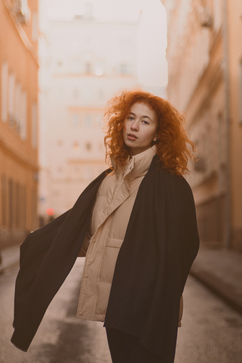 woman in black blazer standing near brown building during daytime