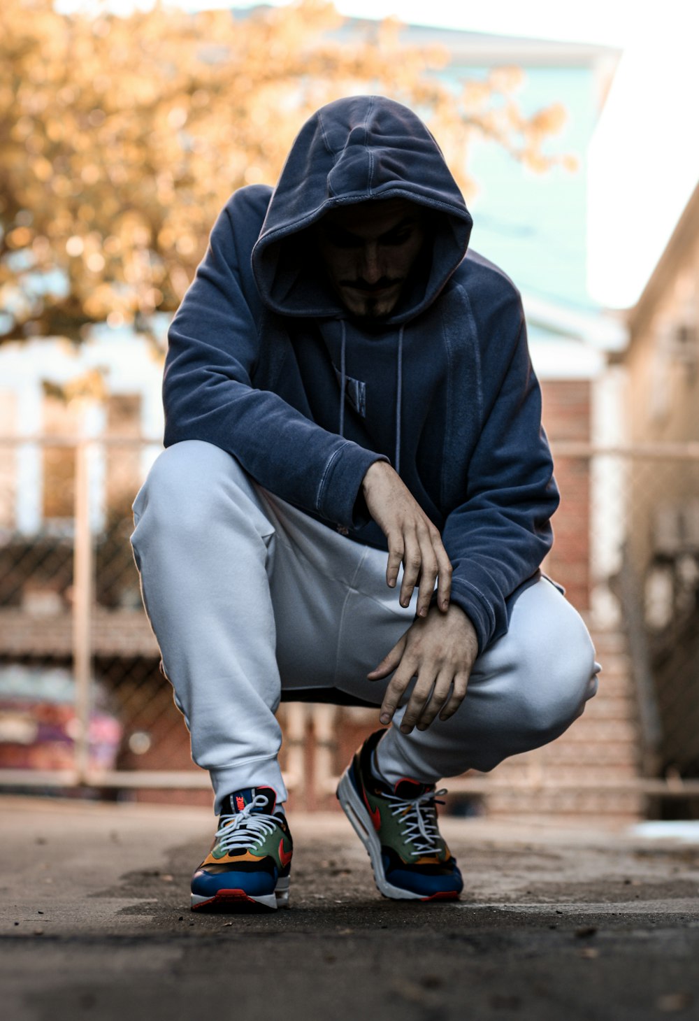man in black hoodie and gray pants sitting on concrete bench during daytime
