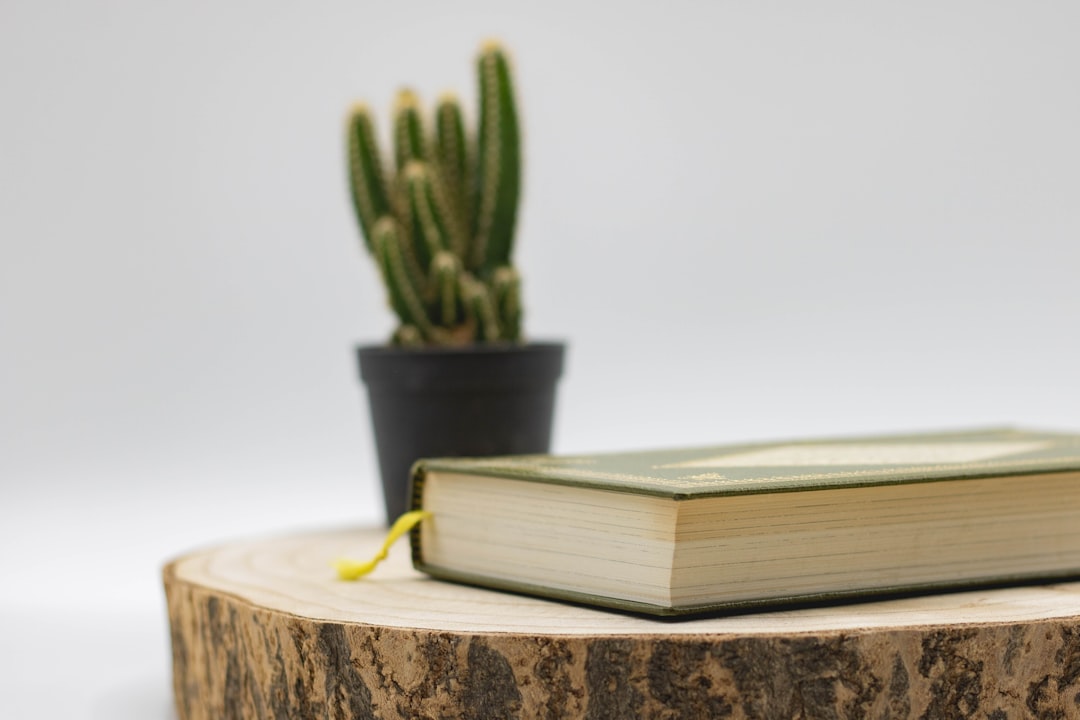 green hardbound book on brown wooden table