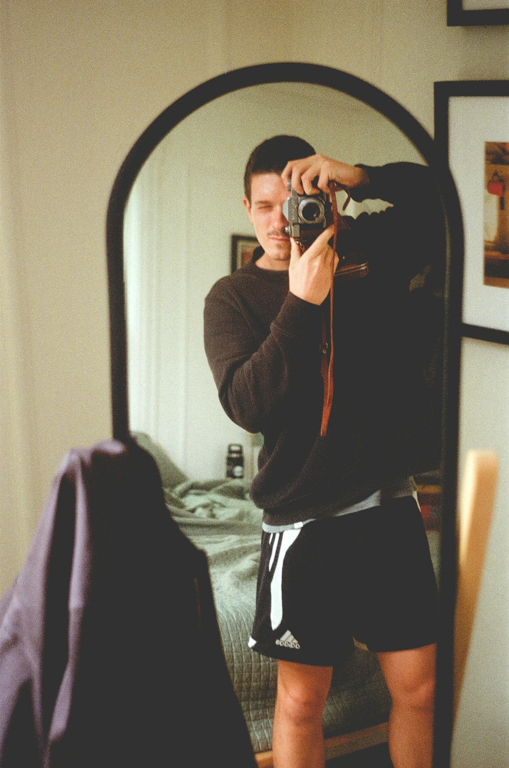 woman in brown jacket taking photo in front of mirror