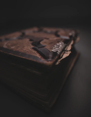 A close-up of an old, weathered book with cryptic symbols and a flickering candle beside it.
